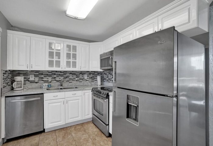 Kitchen at gay-friendly hotel. Stainless steel fridge, oven, dishwasher, and microwave. White cabinets and mosaic backsplash. All-male spa resort.