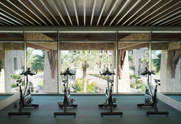 Gym at Sofitel Dubai The Palm Resort & Spa, a gay-friendly hotel, with exercise bikes facing tropical gardens. Fitness for gay men travelers.