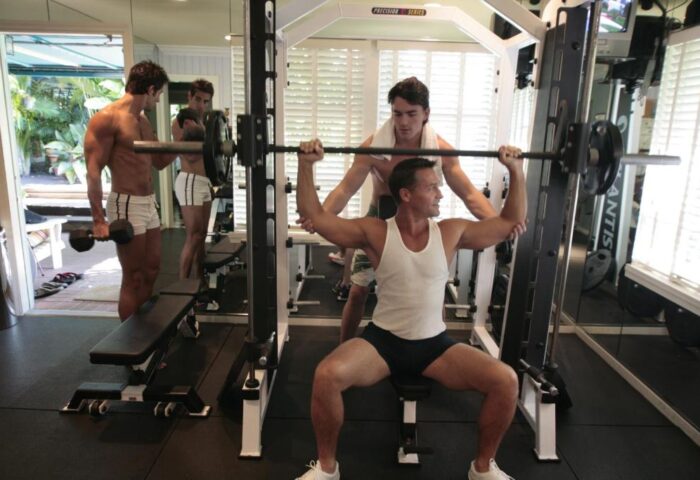 Gay-friendly hotel gym at Pineapple Point Guesthouse. Men working out with weights. Fitness center for gay men's resort in Fort Lauderdale.