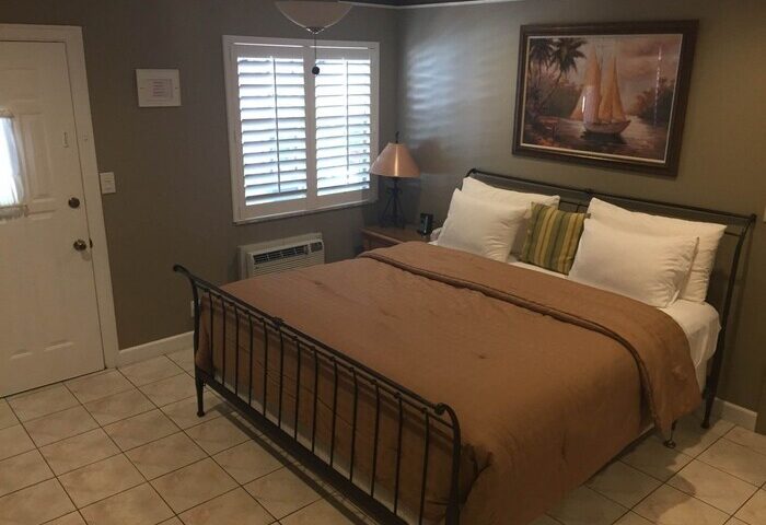 Bedroom at Coral Reef Guesthouse, a gay-friendly hotel. Features a queen bed, tile floor, & sailboat art. Ideal for gay travel.