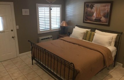 Bedroom at Coral Reef Guesthouse, a gay-friendly hotel. Features a queen bed, tile floor, & sailboat art. Ideal for gay travel.