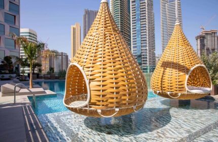 Hotel Indigo Dubai Downtown gay-friendly hotel: Hanging chairs over a pool. Modern Dubai skyline in the background. Gay travel luxury.