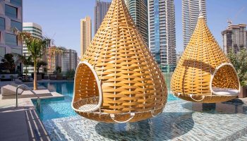 Hotel Indigo Dubai Downtown gay-friendly hotel: Hanging chairs over a pool. Modern Dubai skyline in the background. Gay travel luxury.