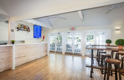 NYAH Key West adults-only gay-friendly hotel bar area. Bar with stools, liquor bottles, menu, and exit to patio. Great for gay men travel.