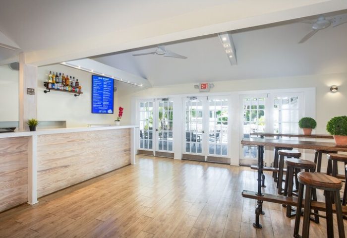 NYAH Key West adults-only gay-friendly hotel bar area. Bar with stools, liquor bottles, menu, and exit to patio. Great for gay men travel.