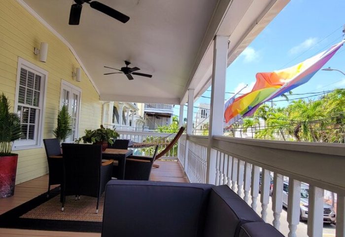 Equator Resort gay-friendly hotel porch view with rainbow flag. Outdoor seating, ceiling fans, and tropical vibe for gay travelers.