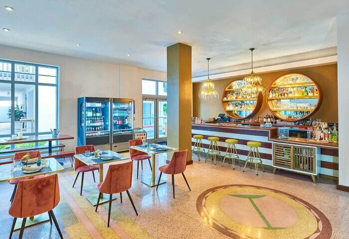 Axel Beach Miami gay-friendly hotel's stylish bar area. Retro design with round shelves, bar stools, and tables. A welcoming space for gay travelers.