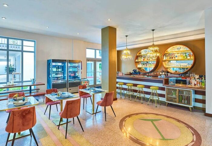 Axel Beach Miami gay-friendly hotel's stylish bar area. Retro design with round shelves, bar stools, and tables. A welcoming space for gay travelers.