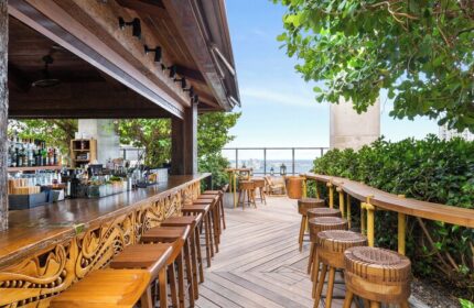 EAST Miami gay-friendly hotel rooftop bar. Outdoor wooden bar stools and counter overlooking the city skyline. Great gay travel spot.