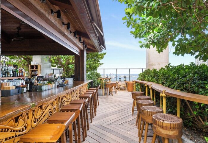 EAST Miami gay-friendly hotel rooftop bar. Outdoor wooden bar stools and counter overlooking the city skyline. Great gay travel spot.