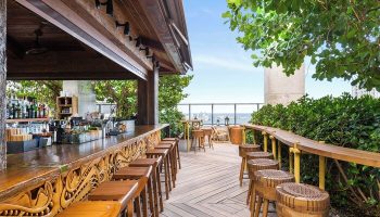 EAST Miami gay-friendly hotel rooftop bar. Outdoor wooden bar stools and counter overlooking the city skyline. Great gay travel spot.
