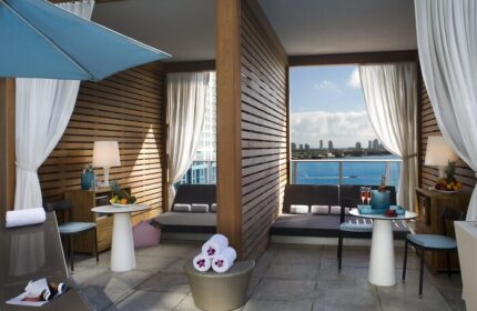 Kimpton EPIC Hotel gay-friendly suite. Balcony cabana with ocean view. Loungers, table, and towels. Luxury gay travel in Miami.