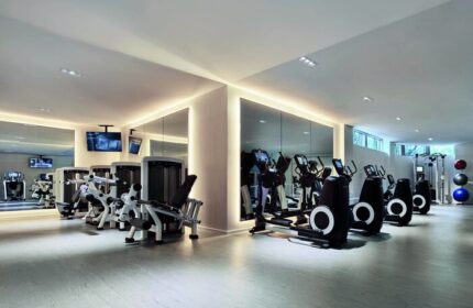 The Miami Beach EDITION's gym. This gay-friendly hotel features modern fitness equipment and mirrored walls, perfect for a workout during your stay.