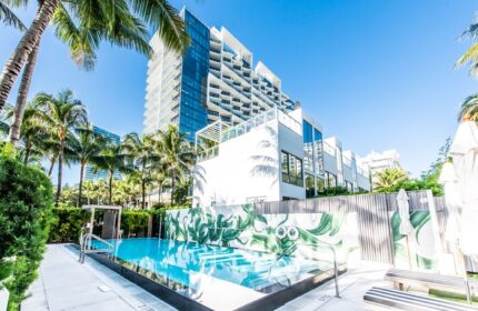W South Beach gay-friendly hotel pool view. Modern architecture, palm trees, and clear blue water create a luxurious, tropical vibe. Miami travel.
