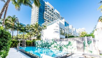W South Beach gay-friendly hotel pool view. Modern architecture, palm trees, and clear blue water create a luxurious, tropical vibe. Miami travel.