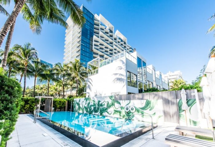 W South Beach gay-friendly hotel pool view. Modern architecture, palm trees, and clear blue water create a luxurious, tropical vibe. Miami travel.