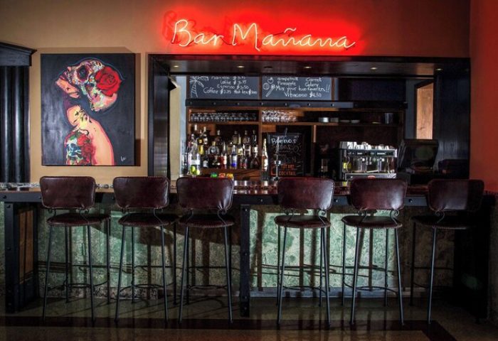 Dream South Beach bar with stools, neon Bar Mañana sign, and skull art. Gay-friendly hotel with a cool, modern vibe. Perfect for gay travel.