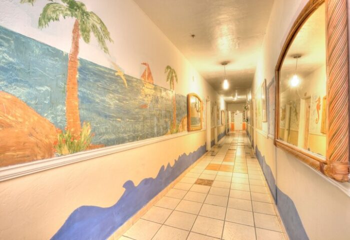 Hallway at James Hotel, a gay-friendly hotel. Mural of tropical beach scene with palm trees, ocean, and sailboat. Mirrors line the walls.