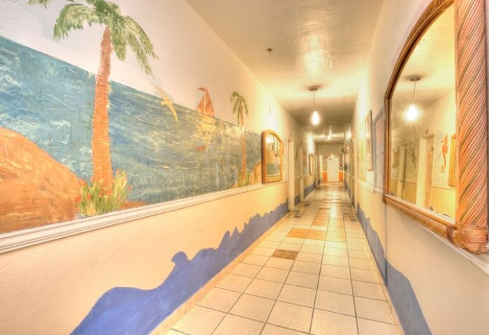 Hallway at James Hotel, a gay-friendly hotel. Mural of tropical beach scene with palm trees, ocean, and sailboat. Mirrors line the walls.
