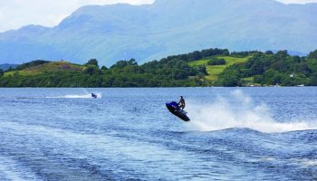 Cameron House on Loch Lomond: Water sports at this gay-friendly hotel. A man rides a jet ski on the loch, with mountains in the background.