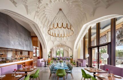 Atlantis The Royal gay-friendly hotel restaurant interior. Ornate ceiling, modern lighting, colorful seating. Gay travel advice.