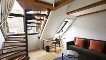 71 Nyhavn Hotel room with spiral staircase, desk, and sofa. Gay-friendly, pet-friendly hotel interior. Cozy, stylish design.