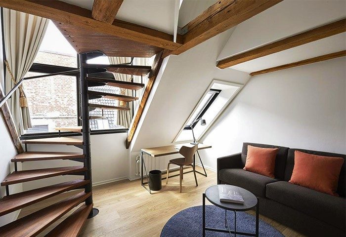 71 Nyhavn Hotel room with spiral staircase, desk, and sofa. Gay-friendly, pet-friendly hotel interior. Cozy, stylish design.