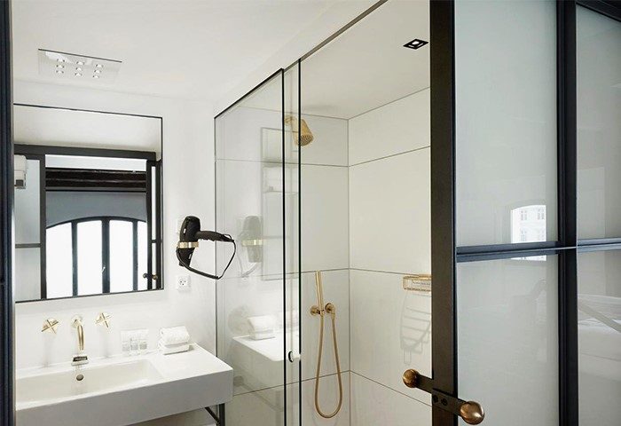 Bathroom at 71 Nyhavn Hotel, a gay-friendly, pet-friendly hotel. Features a sleek sink, mirror, and glass shower. Modern design elements.