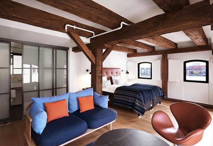 71 Nyhavn Hotel room: Beams, blue sofa, bed, and windows. Gay-friendly, pet-friendly hotel interior. Cozy, stylish design. Perfect for gay travel.