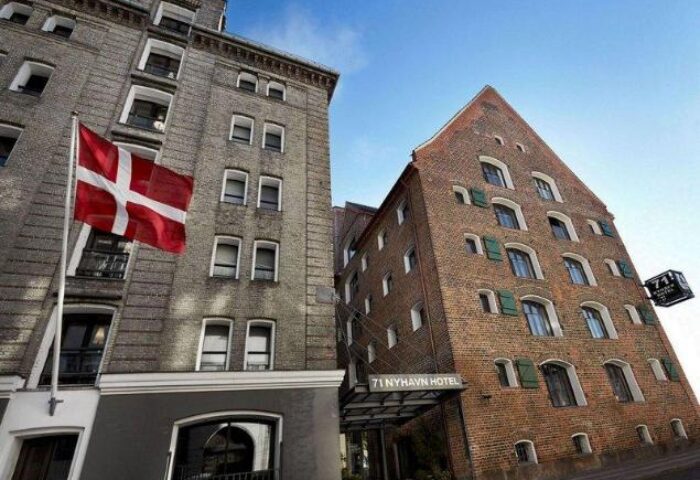 Exterior of 71 Nyhavn Hotel, a gay-friendly and pet-friendly hotel in Copenhagen, Denmark. Danish flag is visible. Brick building.