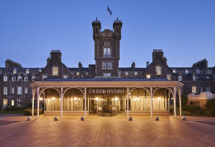 Crieff Hydro hotel exterior at dusk. Gay-friendly hotel with tower, entrance, and brick path. A great place for gay men to travel and visit.
