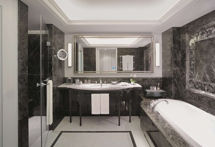 Shangri-La Bosphorus, Istanbul gay-friendly hotel bathroom. Dark marble walls, white tub, sink, and shower. Luxury travel for gay men.