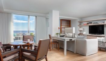 Modern Honolulu Hilton Vacation Club suite living area. Ocean view, desk, TV. Gay-friendly hotel room interior.