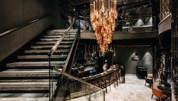 Elysium Taksim Hotel interior. Stairs lead to a bar under a chandelier. Gay-friendly hotel in Istanbul, Turkey. Upscale travel for gay men.