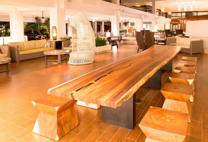 Lobby seating area at Waikiki Beach Marriott Resort & Spa, a gay-friendly hotel. Features a long wooden table and unique wooden stool seating.