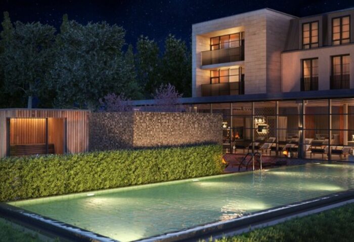 Schloss Roxburghe Hotel's gay-friendly outdoor pool at night. Modern building with sauna, lounge chairs, and starry sky. Luxury gay travel.