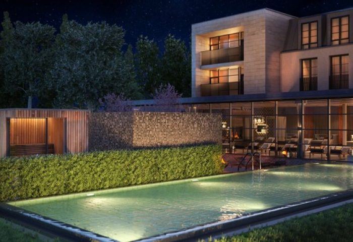 Schloss Roxburghe Hotel's gay-friendly outdoor pool at night. Modern building with sauna, lounge chairs, and starry sky. Luxury gay travel.