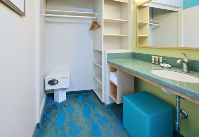Aston Waikiki Circle Hotel's gay-friendly room: closet with safe, shelves, vanity with sink, mirror, stool, & blue wave carpet.