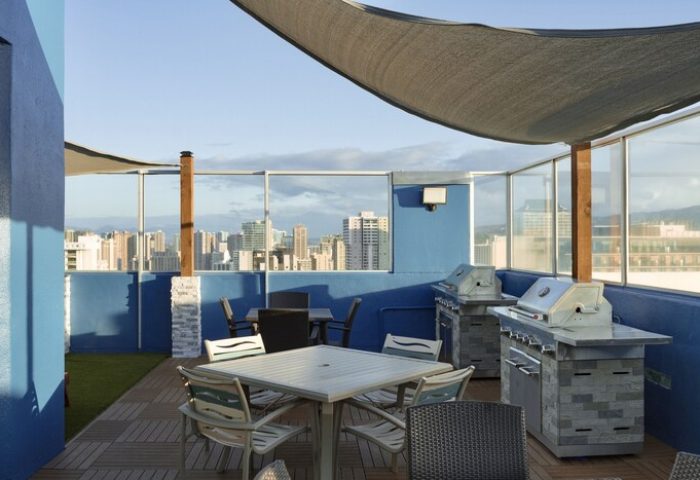 Pacific Monarch Hotel's rooftop deck with grills, tables, and city views. A gay-friendly hotel offering unique amenities for travelers.