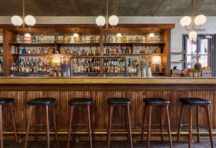 The Hoxton, Holborn bar. Gay-friendly hotel bar with stools, bottles, and warm lighting. A welcoming space for gay men travelers.