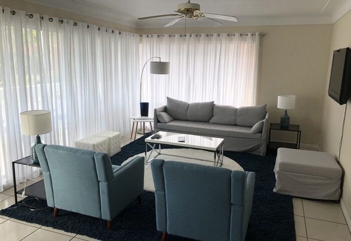 Cheston House, a gay-friendly hotel. Living room area with sofa, chairs, and TV. Clothing optional all-male guesthouse.