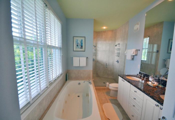 Bathroom at Pineapple Point Guesthouse, a gay men's resort. Features a tub, shower, double vanity, & large window. Gay-Friendly Hotel.