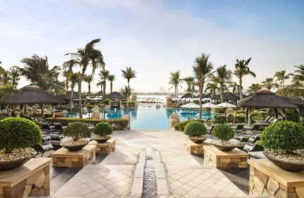 Sofitel Dubai The Palm Resort pool view. Gay-friendly hotel with palm trees, cabanas, and lounge chairs. Perfect for gay travelers' relaxation.
