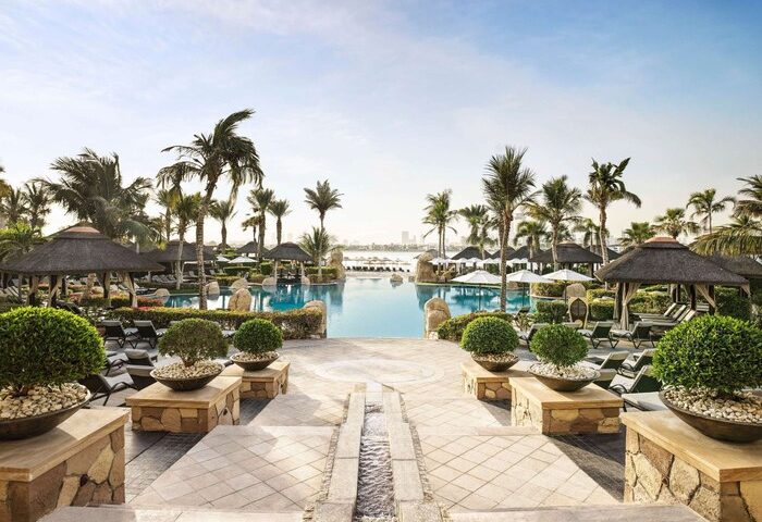 Sofitel Dubai The Palm Resort pool view. Gay-friendly hotel with palm trees, cabanas, and lounge chairs. Perfect for gay travelers' relaxation.