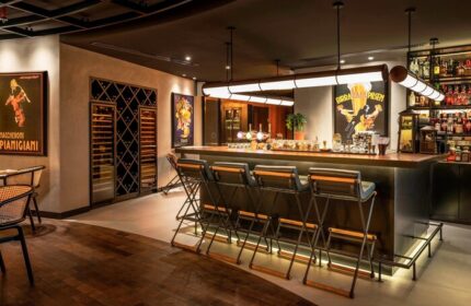 Le Royal Meridien Beach Resort & Spa's bar. Gay-friendly hotel bar interior with stools, vintage posters, and liquor bottles. Elegant, stylish.