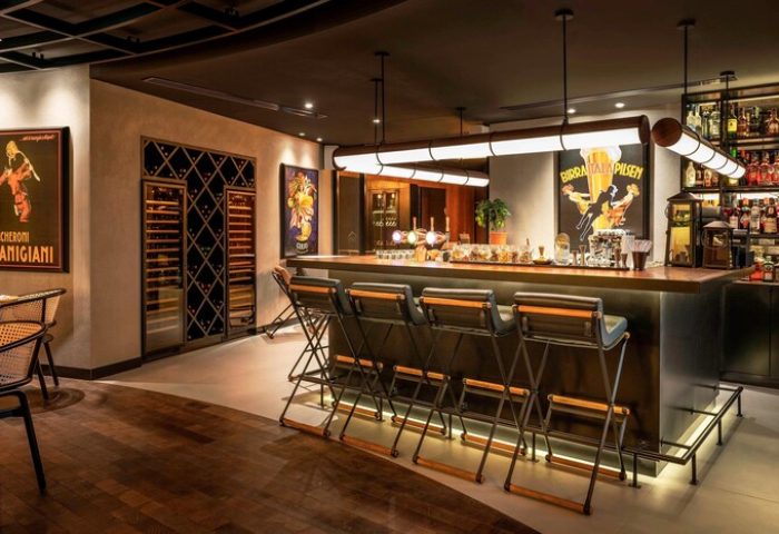 Le Royal Meridien Beach Resort & Spa's bar. Gay-friendly hotel bar interior with stools, vintage posters, and liquor bottles. Elegant, stylish.