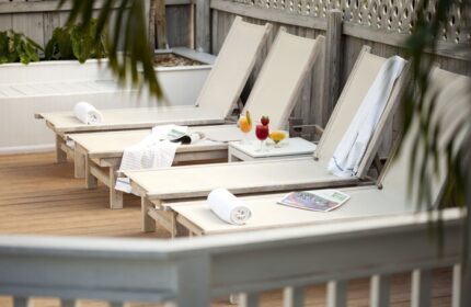 Alexander's Guesthouse gay-friendly hotel: lounge chairs, drinks, and towels on a wooden deck. Perfect for gay men's travel relaxation.