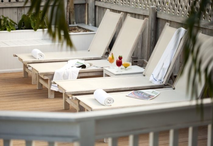 Alexander's Guesthouse gay-friendly hotel: lounge chairs, drinks, and towels on a wooden deck. Perfect for gay men's travel relaxation.