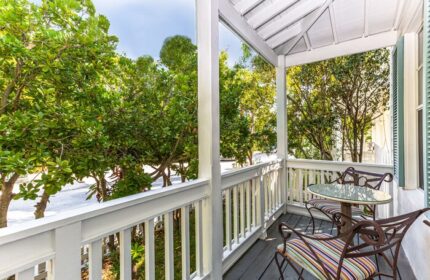 Balcony at The Paradise Inn, a gay-friendly, adults-only hotel. Table and chairs overlook lush trees. Relaxing vacation spot.