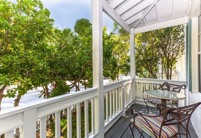 Balcony at The Paradise Inn, a gay-friendly, adults-only hotel. Table and chairs overlook lush trees. Relaxing vacation spot.